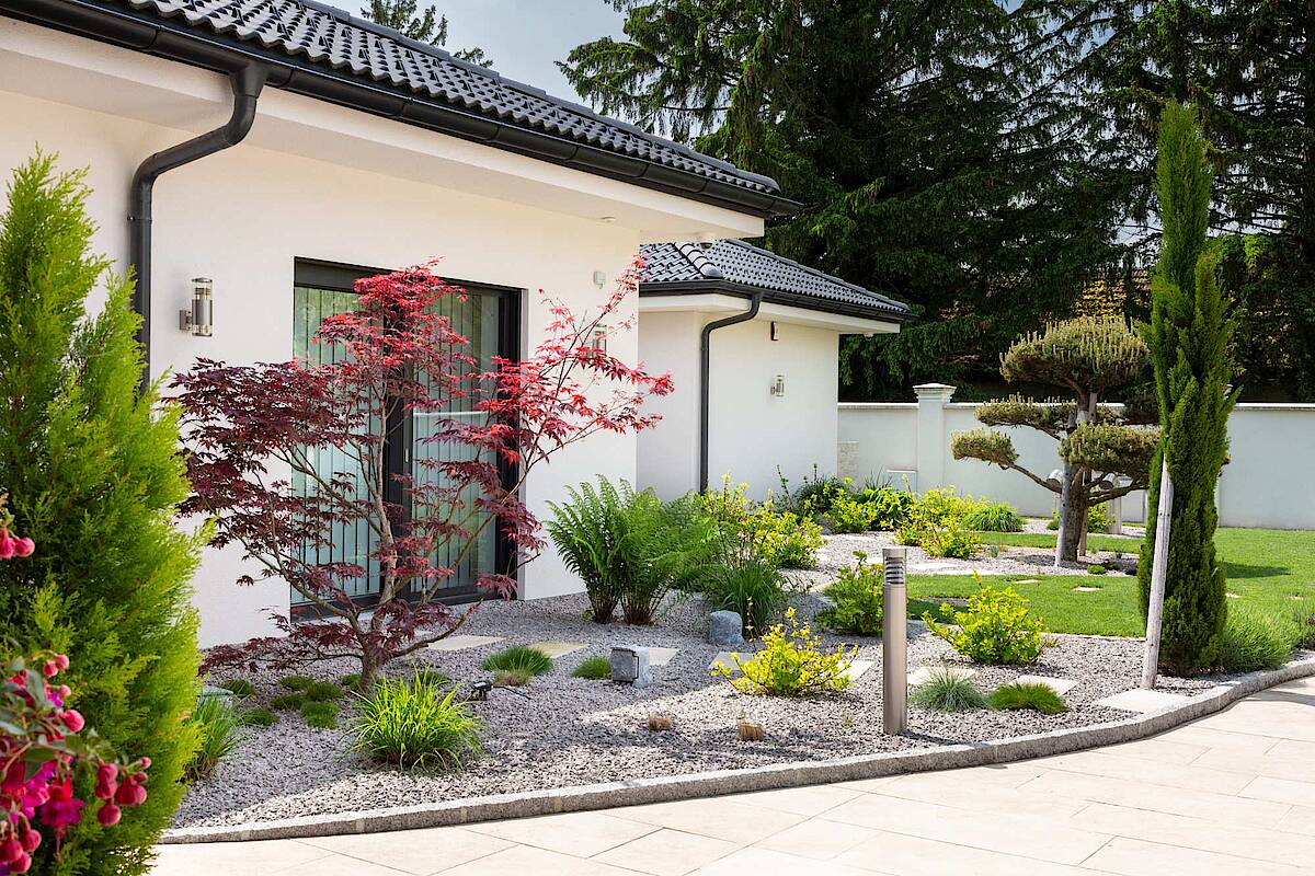 Steingarten mit Bepflanzung, Haus im Hintergrund