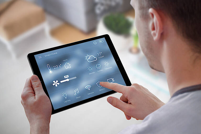 Mann bedient ein Tablet mit Smart-Home-Steuerung