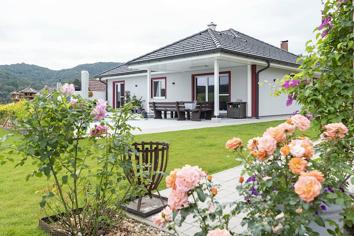 Blick auf die Terrasse des Bungalows, Rosenbüsche im Vordergrund