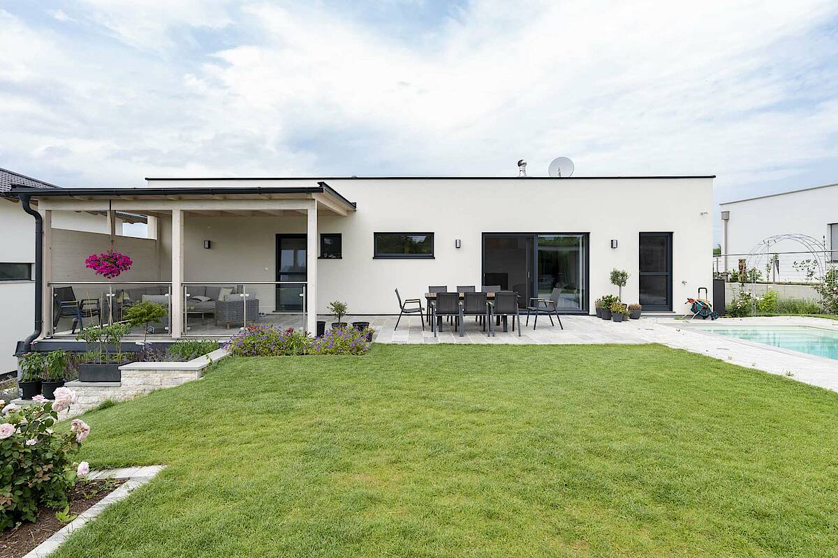 Blick vom Garten auf das Haus, komplette Seite ist Terrasse, Pool rechts im Bild