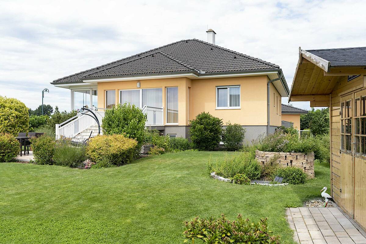 Blick auf das Haus aus dem Garten. Verglaster Balkon links, Gartenhaus rechts im Bild