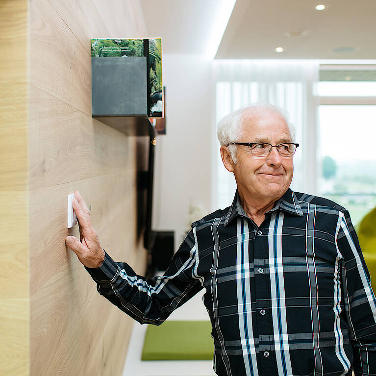 Älterer Mann bedient einen Lichtschalter für seine Loxone Beleuchtung