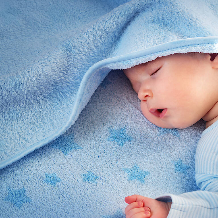 Schlafendes Baby mit hellblauer Decke
