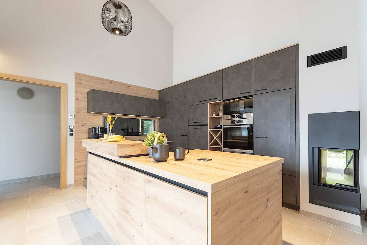 Küche mit Kücheninsel aus Holz, Kamin im Bild rechts