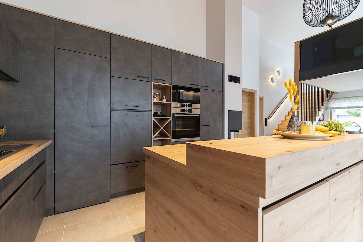 Küche mit schwarzen Möbeln, Kücheninsel aus Holz. Treppe zu Galerie rechts im Hintergrund