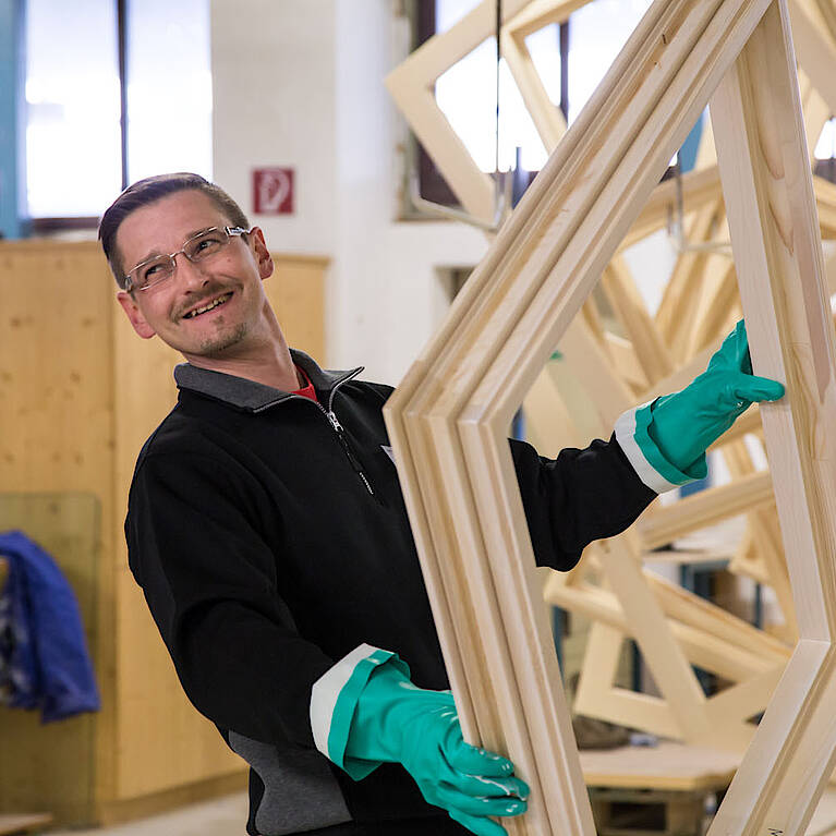 Lachender Hartl Haus Mitarbeiter mit Fensterrahmen in den Händen