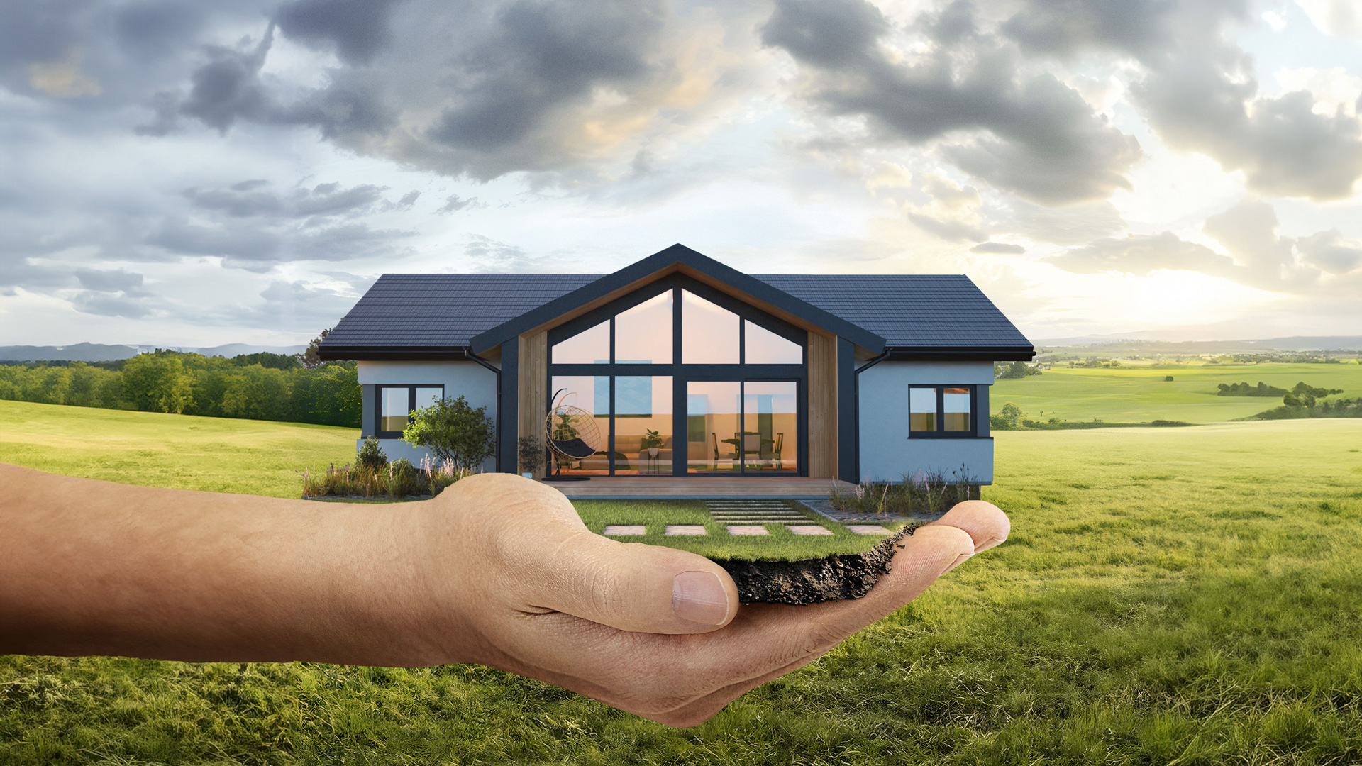 Symbolbild: Hand hält modernes Haus in grüner Landschaft